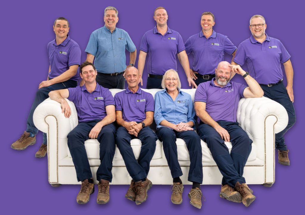 A photo of the Conquer Termites team sitting and standing around a sofa looking happy