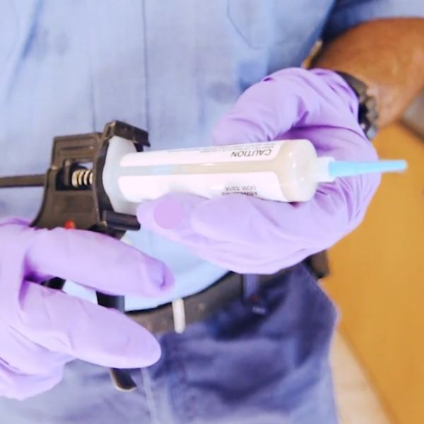 Photo of a Conquer Termites technician holding a cockroach bait gel gun
