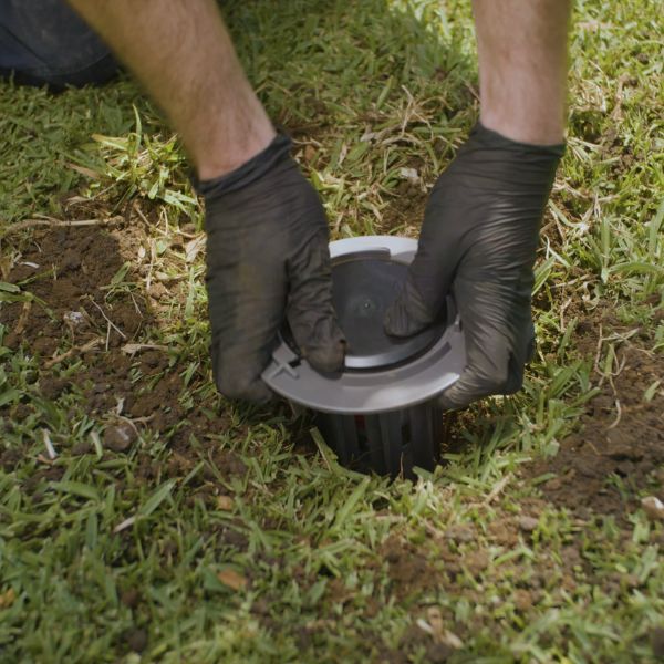 A Conquer Termite technician installing a Trelona inground bait station in Brisbane